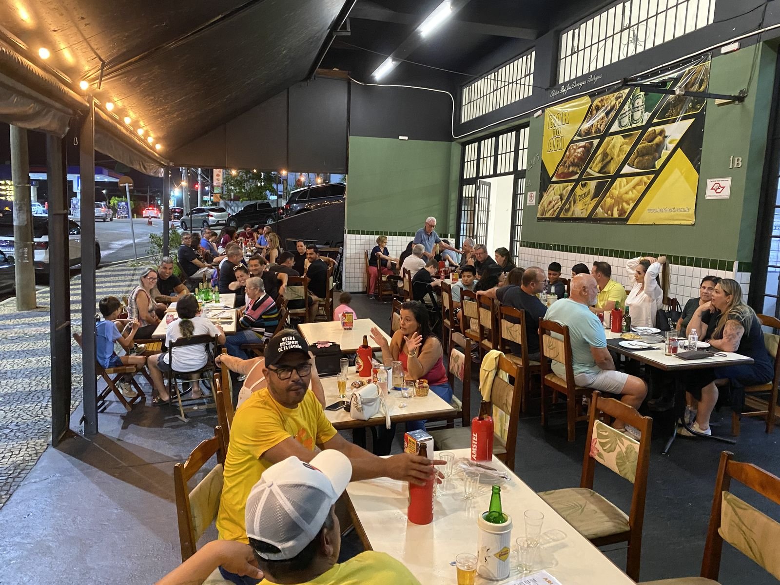 Mesas cheias na calçada do Bar do Ari em uma noite de movimento em Valinhos