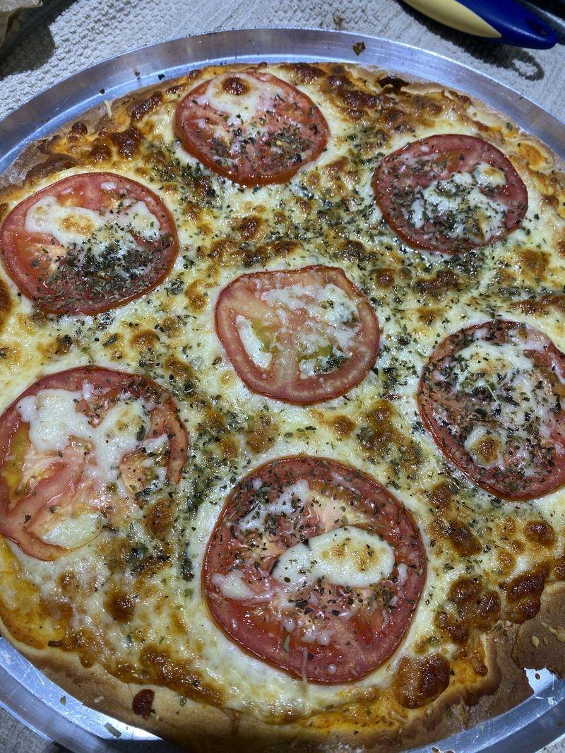 Pizza marguerita com rodelas de tomate, muçarela e orégano na assadeira